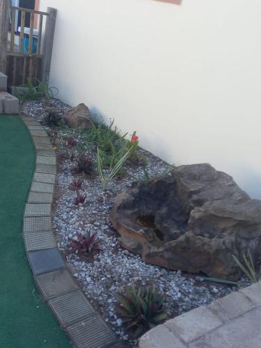 a garden with a large rock and some plants at Ocean Wave Chalets Unit 2 in Hibberdene