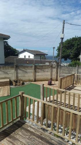 a person sitting on a deck next to a wooden fence at Ocean Wave Chalets Unit 2 in Hibberdene