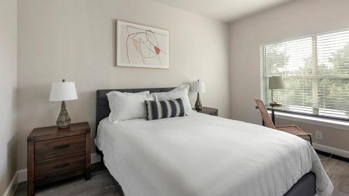 a bedroom with a white bed and a window at Landing at Residences at River Park West - Richmond in Richmond