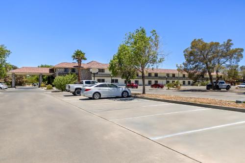 a parking lot with cars parked in front of a building at HomeTowne Studios by Red Roof Ridgecrest in Ridgecrest