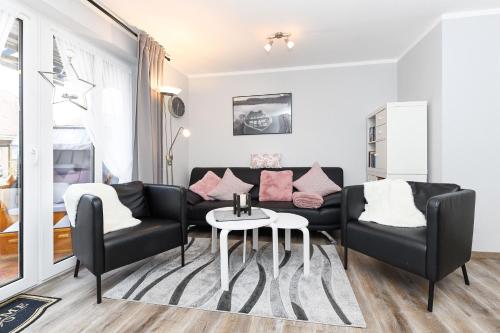 Una sala de estar con un sofá negro y una mesa. en Ferienhaus Strandidylle, en Carolinensiel