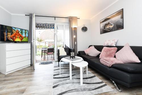 Una sala de estar con un sofá negro y una mesa. en Ferienhaus Strandidylle, en Carolinensiel