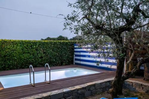 a swimming pool with two metal rails next to a tree at Casa Fra Gli Ulivi with Private Pool - Chicca in Ameglia