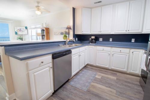 a kitchen with white cabinets and a sink at Sand Castle in the Sky in Folly Beach