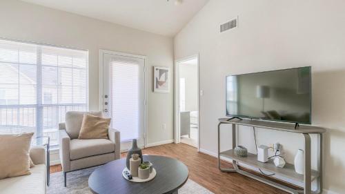 a living room with a tv and a chair and a table at Landing at Settlers Ranch - Pasadena in Houston