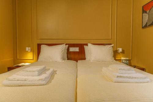 two beds in a hotel room with towels on them at Fly House Faro in FAO