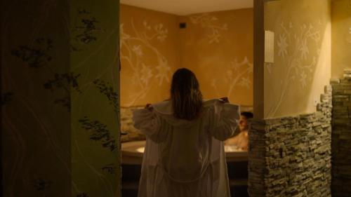 a woman standing in a bathroom looking into a mirror at T'AMI Hotel Resort Spa in Selvino