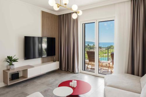 a living room with a couch and a tv and a balcony at Lustica Bay Centrale by 2BHome in Tivat