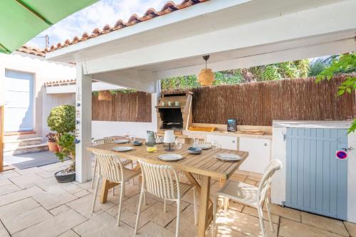 Una cocina al aire libre con una mesa y sillas de madera. en Villa Azul - Welkeys, en Bandol