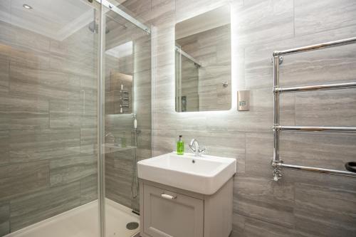 a white bathroom with a sink and a shower at Luxury Holidays Yorkshire - Bancroft Cottage in Bedale