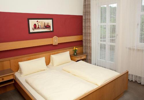 two beds in a room with a red wall at Scheffel - Gasthof in Gößweinstein
