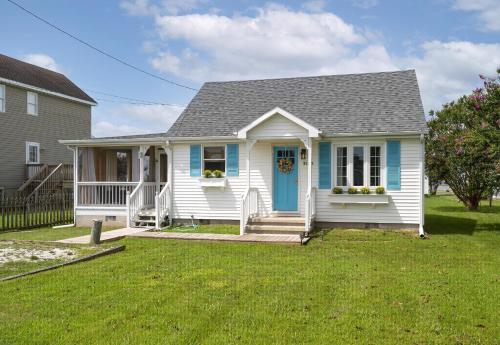 a small white house with a blue door at Bertie Street Cottage in Chincoteague