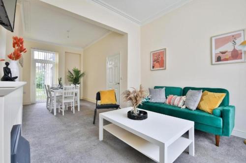 a living room with a green couch and a table at Family-Friendly Cardiff Comfort! in Cardiff