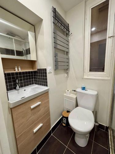 une salle de bain avec des toilettes blanches et un lavabo dans l'établissement Appartement Commerce Tour Eiffel, à Paris
