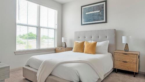 a white bedroom with a bed and a window at Landing Apartments Austin - Pflugerville in Pflugerville