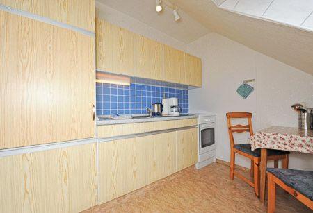 a kitchen with wooden cabinets and a table with a chair at Landhaus Schwanenhof in Ostbense in Westbense