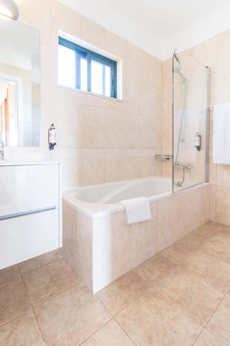 a white bathroom with a tub and a shower at Pestana Gramacho Residences in Ferragudo