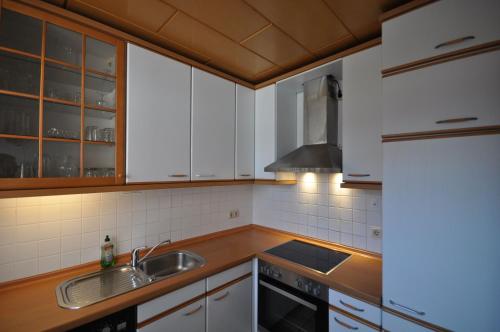 a kitchen with white cabinets and a sink at Nr 26 - Ferienhaus Bootsweg in Harlesiel