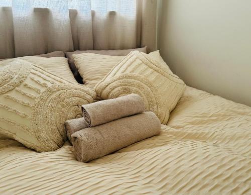 1 cama con 3 toallas y almohadas en Niizala Apartments, en Windhoek