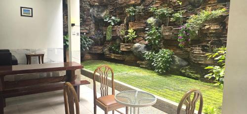 a room with a table and chairs and a stone wall at Ease Living Palem Kenari in Jatirarangan