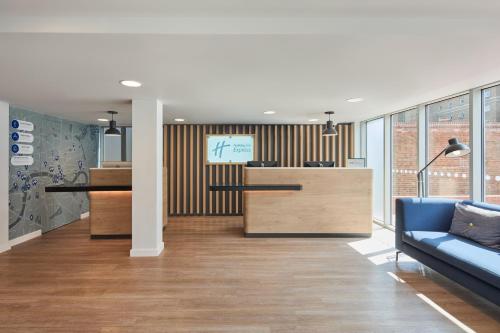 an office lobby with a blue couch and a desk at Holiday Inn Express London Limehouse by IHG in London