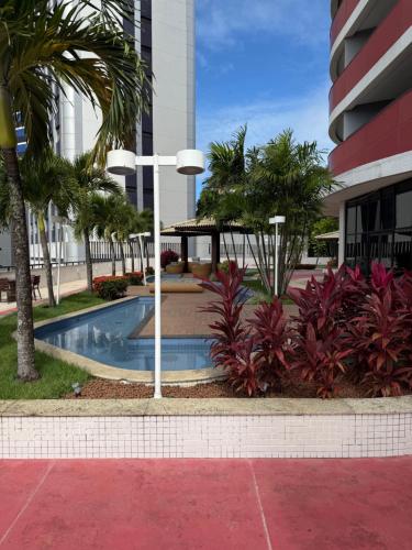 a courtyard with a pool in a building with palm trees at Mercure Boulevard Salvador Hotel 20 Andar in Salvador