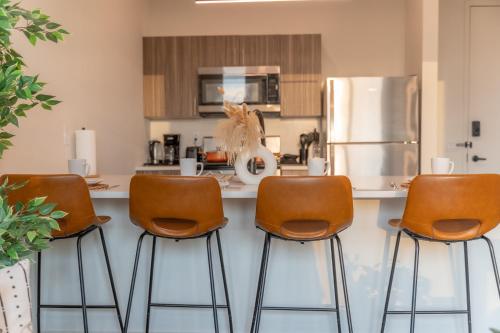 a kitchen with three bar stools and a refrigerator at 2 Queen Bed with Free Parking, NYC View, Near Train Station in East Orange