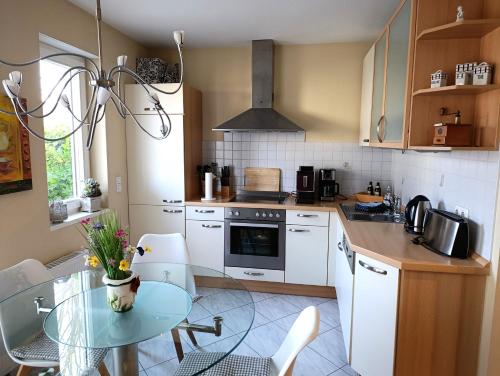 una piccola cucina con tavolo in vetro e piano cottura di Residenz Strandkrone 03 a Kühlungsborn