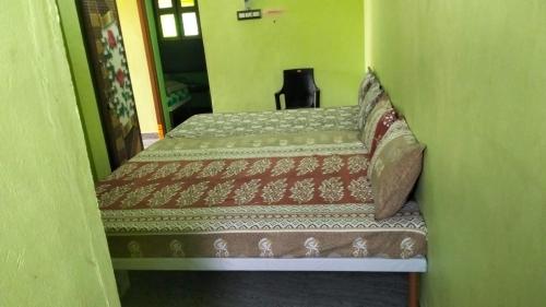 two beds in a small room with a chair at OM Karam Home stay in Tiruvannāmalai