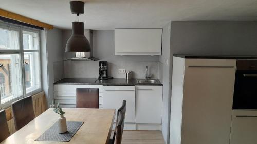 a kitchen with white cabinets and a wooden table at Ferienhaus Bär in Bizau