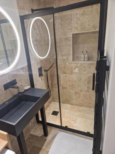 La salle de bains est pourvue d'une douche et d'un lavabo noir. dans l'établissement Les Studios Famandiers, à Saint-Raphaël