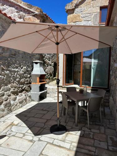 a table and chairs under an umbrella on a patio at Casa de Lamalonga T1 in Campos