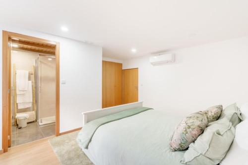 a white bedroom with a bed and a bathroom at Casa de Lamalonga T1 in Campos