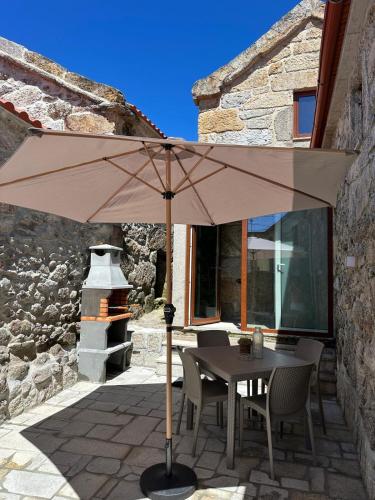 a table and chairs under an umbrella on a patio at Casa de Lamalonga T1 in Campos