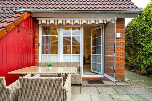 un patio avec une table et des chaises devant une maison dans l'établissement Von Manderley, Ferienhaus mit 3 Schlafzimmern und Garten, Hund willkommen!, à Greetsiel