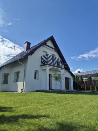 a white house with a lawn in front of it at Przystanek Osłonin- całoroczny dom na wynajem in Osłonin