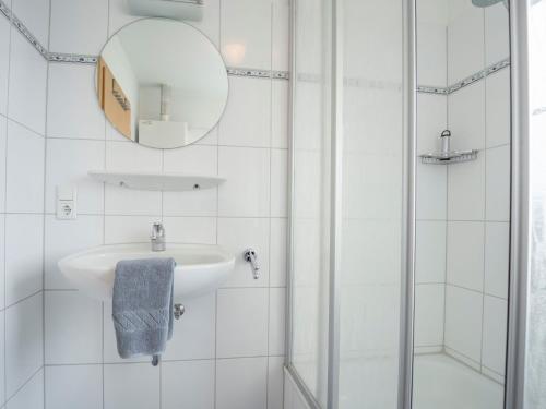a white bathroom with a sink and a mirror at Ferienhäuser Greetsiel in Ostfriesland in Greetsiel