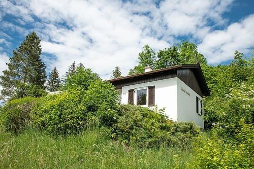a small white house in the middle of a field at Ferienhäuser im Feriendorf Weissensee im Allgäu F2 in Füssen