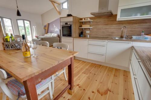 a kitchen with a wooden table with a bottle of wine at Das Backsteinhus, App Utkiek in Dargen