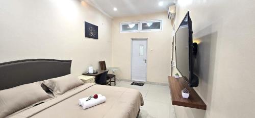 a room with a bed and a television in it at Ease Living Palem Kenari in Jatirarangan