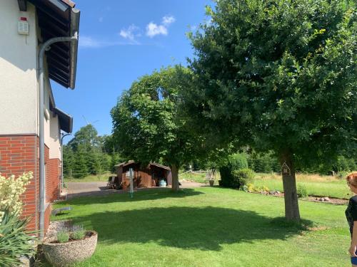 a woman standing in front of a yard with a tree at Ferienwohnung bei Besten in Sachsenhausen