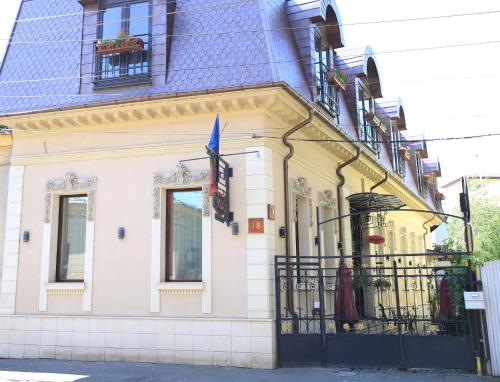 a yellow and white building with a black gate at Vila Sia in Bucharest