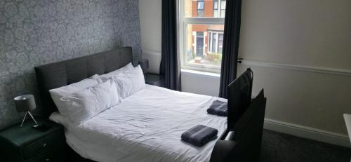 ein Schlafzimmer mit einem Bett mit weißen Laken und einem Fenster in der Unterkunft Stunning Spacious Home Close to Blackpool Beach in Blackpool