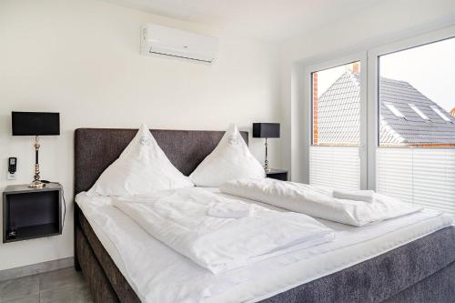 a bed with white sheets and a tv in a room at Die Zimmerei 5, zentrale Lage, Obergeschoss mit Balkon in Greetsiel