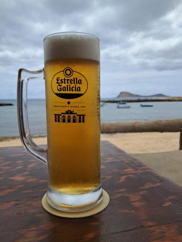 a glass of beer sitting on a table near the beach at Vivenda Mia in Beirona