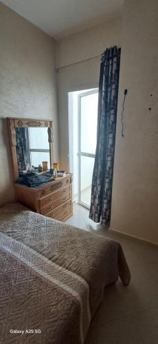 a bedroom with a bed and a dresser and a window at Golf msnana in Tangier