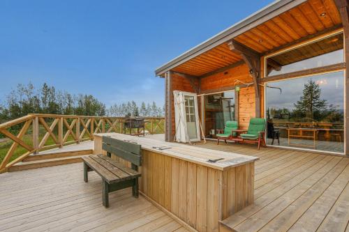 a wooden deck with a bench and a house at Riverside Cabin - Hot Tub, Fishing and Relaxing Escape in Laugarvatn