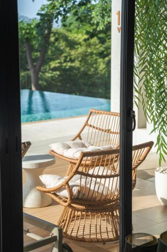 a wicker rocking chair on a patio with a pool at Epic Tamarindo Boutique Hotel in Tamarindo