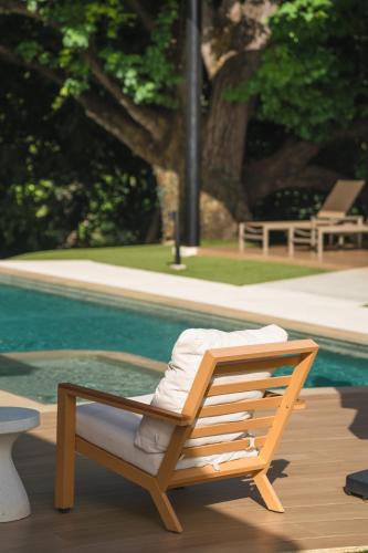 a wooden lounge chair sitting next to a pool at Epic Tamarindo Boutique Hotel in Tamarindo