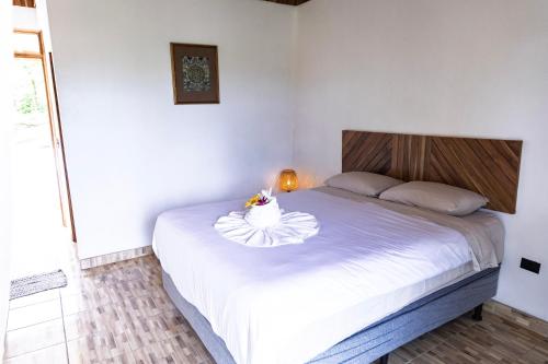 a bedroom with a white bed with a bowl of flowers on it at Essence Arenal Spa & Yoga in El Castillo de La Fortuna